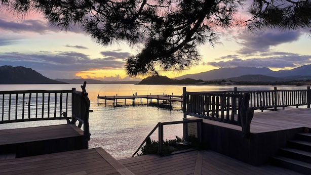 A wooden pier extending into calm water with a sunset in the background. - Cozy villa 🌞, air-conditioned, 5' walk to San Ciprianu beach 🌊 (Lecci)