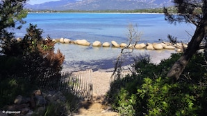 A clear view of a lake with a wooden fence and rocks in the foreground, surrounded by trees and mountains in the background. - Cozy villa 🌞, air-conditioned, 5' walk to San Ciprianu beach 🌊 (Lecci)