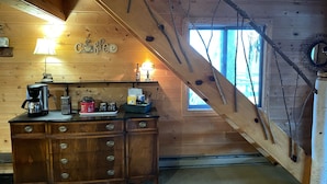 Une charmante cabane en bois avec un escalier en bois, un coin café et une fenêtre offrant une belle vue.