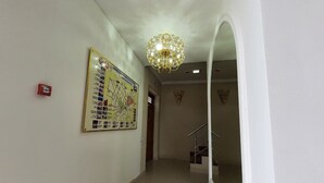 A hallway with a chandelier, a map on the wall, and a staircase. - Hotel Diyor (Samarkand)