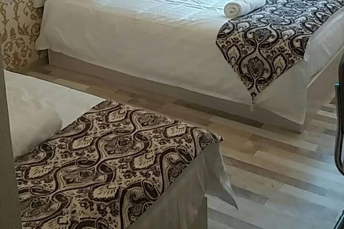 Habitación de hotel con dos camas, cortinas estampadas y un radiador.