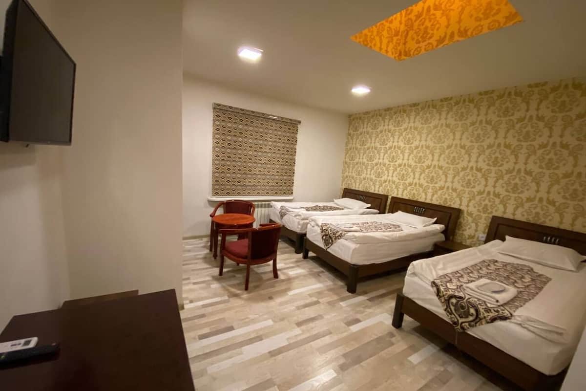Una habitación de hotel con dos camas, un escritorio, una silla y un televisor.