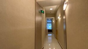 A long, narrow hallway with a shiny floor, walls with a textured finish, and a ceiling with recessed lighting. - Hotel Diyor (Samarkand)