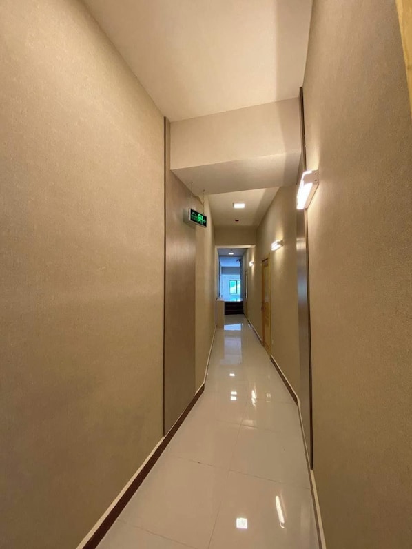 A long, narrow hallway with a shiny floor, walls with a textured finish, and a ceiling with recessed lighting. - Hotel Diyor (Samarkand)