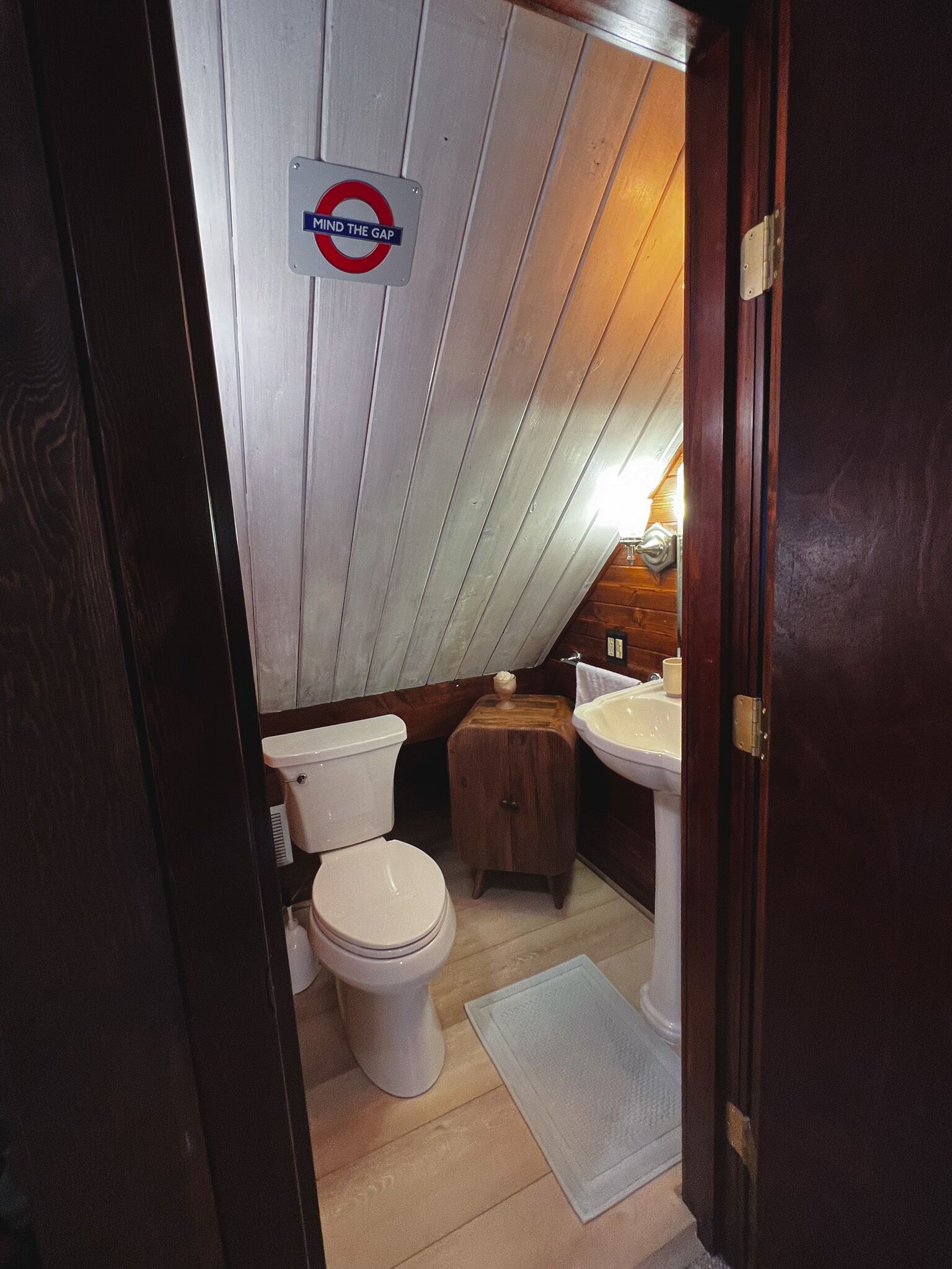 Ein kleines Badezimmer mit Toilette, einem Holzkästen und einem Waschbecken.