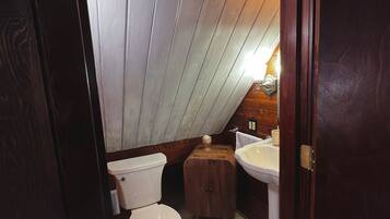 Ein kleines Badezimmer mit Toilette, einem Holzkästen und einem Waschbecken.