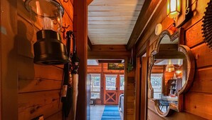 Un pasillo de madera con un banco, un espejo y una puerta que da a una habitación con un tapete azul.