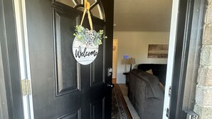 A black door with a 'Welcome' sign and a hanging decoration.