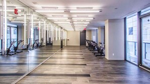 A gym with exercise bikes lined up along the walls, a mirrored wall, and a wooden floor.