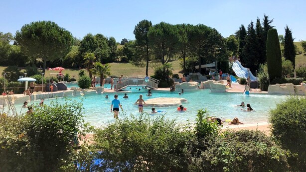 Un espace piscine doté de plusieurs toboggans et d’un pont.