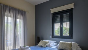 A double bed with a blue bedspread, two white pillows, and two folded towels on the bed. - Smaris Collection luxury villas.Sea side villa 5 min.from the beach ! (Σίσι)