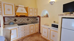 A compact kitchen with white cabinets, a gas stove, a microwave, and a refrigerator.