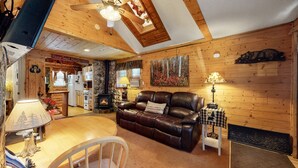 Un intérieur de chalet chaleureux avec une cheminée en pierre, un canapé en cuir et un coin repas.