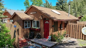 Une petite cabane en bois avec une porte rouge, une pancarte indiquant «Bienvenue» et une boîte aux lettres.