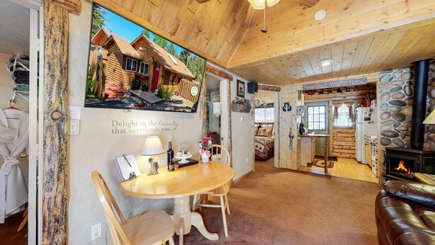 L’intérieur d’un chalet accueillant, avec un coin repas, une cheminée et un mur en pierre.