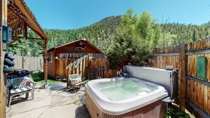 Une cabane en bois dotée d’un bain à remous et d’une terrasse couverte.