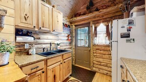 Une cuisine rustique dans un chalet, avec des meubles en bois, un évier et un réfrigérateur.