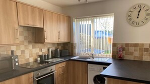 Une cuisine moderne avec des meubles en bois, un four encastré, un lave-vaisselle et un lave-linge.