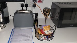 Una encimera de cocina con un tostador, un microondas, una cafetera y una cesta de aperitivos.