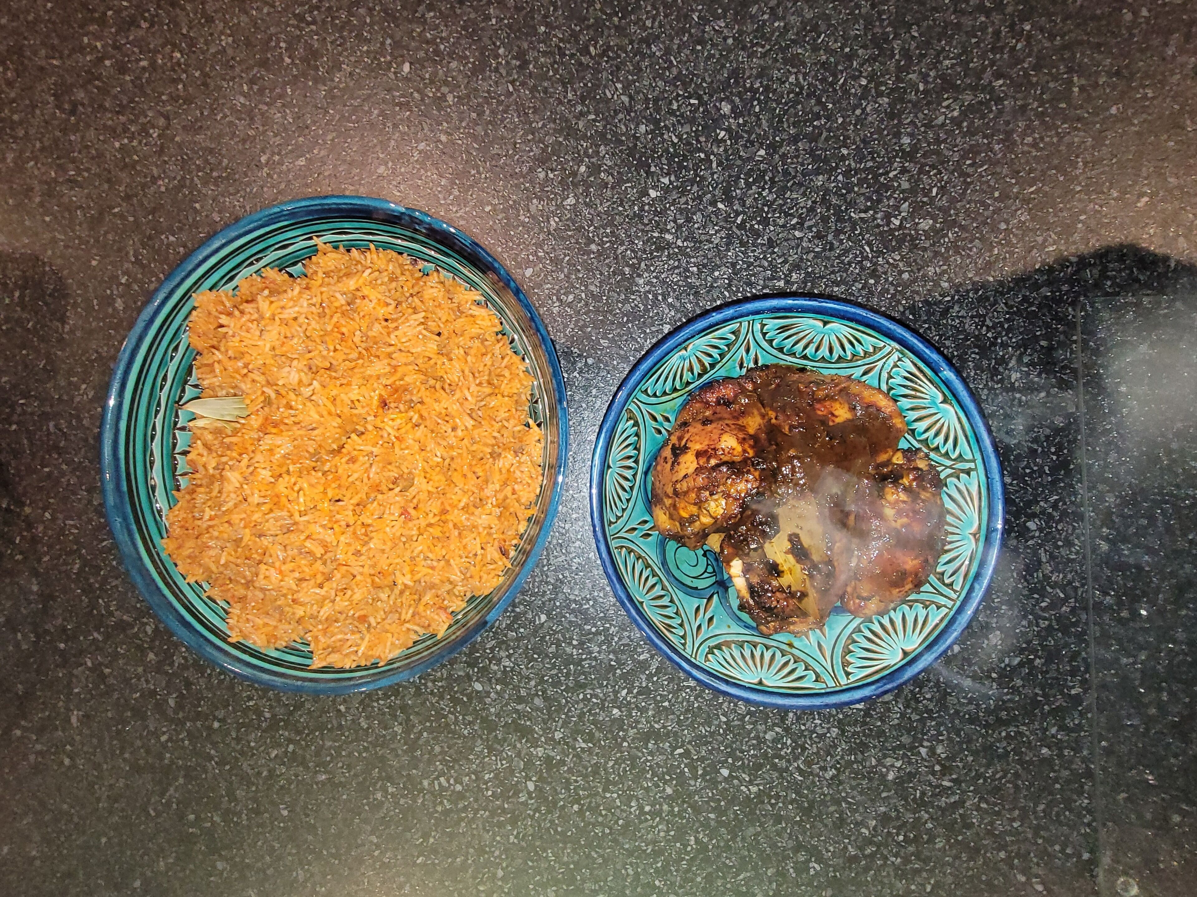 Two dishes, one with rice and the other with meat, on a textured surface.