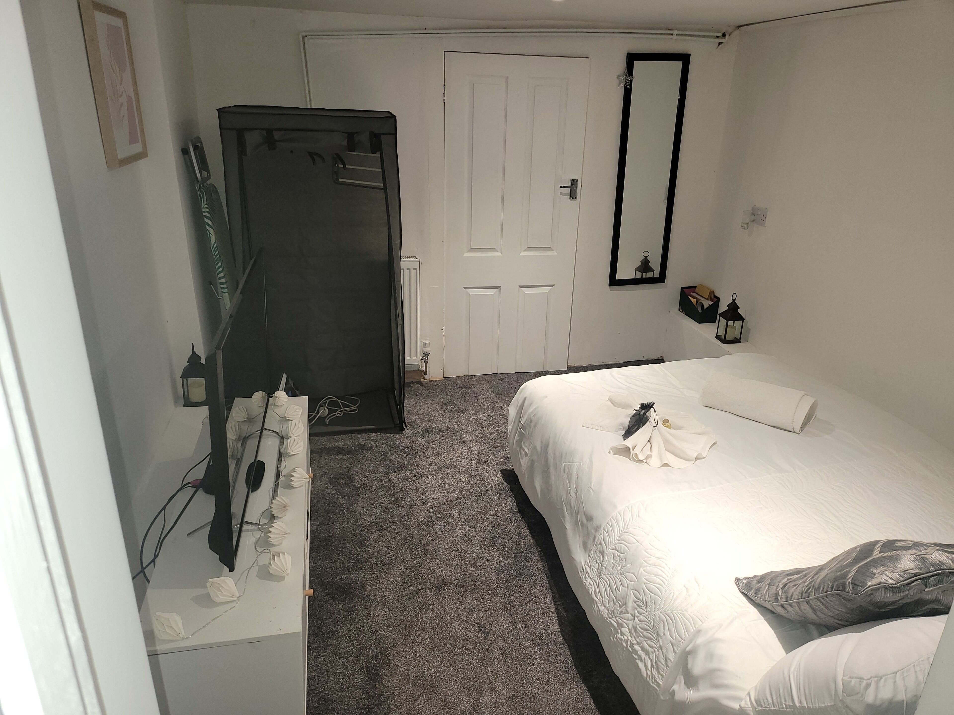 A bedroom with a bed, a wardrobe, a door, and a mirror.