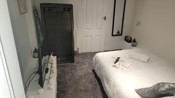 A bedroom with a bed, a wardrobe, a door, and a mirror.