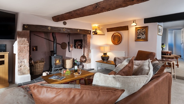 A cozy living room with a fireplace, a sofa, and a television. - The Snuggery a Cosy Country Cottage (Wellington)