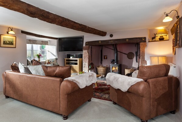 A cozy living room with brown leather sofas, a fireplace, and a television.
