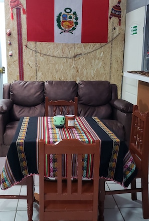 Relax in the living area with a sofa, chair, and throw blanket, accompanied by a table and two cups.