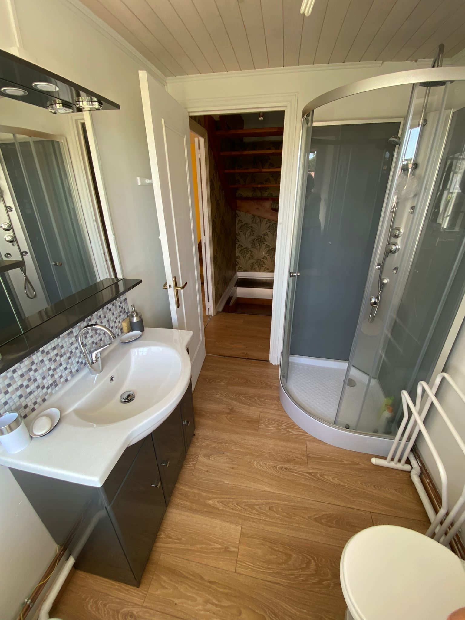 Een moderne badkamer met een witte wastafel, spiegel en douche.