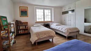 Une chambre avec deux lits, une bibliothèque, une fenêtre et une armoire.