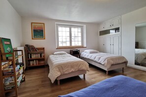 Ein Schlafzimmer mit zwei Betten, einem Bücherregal, einem Fenster und einem Kleiderschrank.