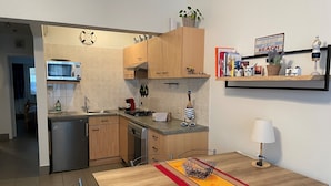Une cuisine moderne avec des meubles en bois, un four à micro-ondes, un évier et une cuisinière. On y trouve une table à manger avec des chaises et un vase décoratif.