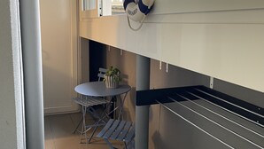 Un balcon avec une table et des chaises, un gilet de sauvetage suspendu et une fenêtre donnant sur un immeuble.