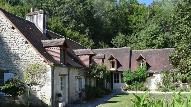 A stone building with a sloped roof, a small garden, and a pathway leading to the entrance. - Moulin des Arts (Loché-sur-Indrois)