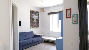 Een moderne woonkamer met een blauwe bank, een bijzettafeltje en een raam met uitzicht.