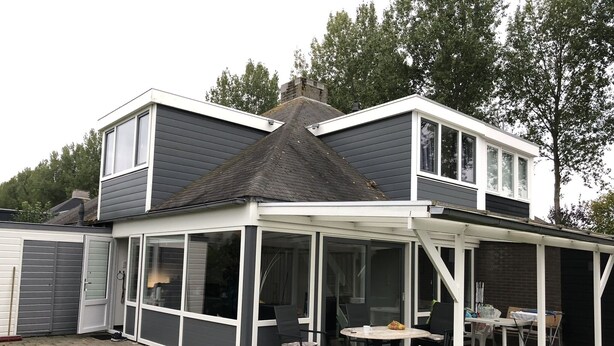 Une maison à deux étages dotée d’un patio couvert.