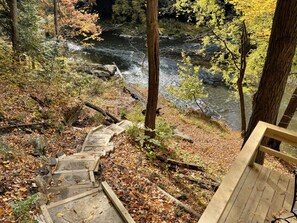 A wooden staircase leading to a deck overlooking a river.