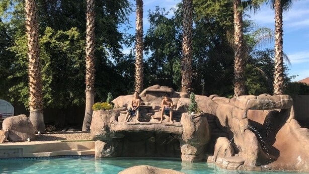Ein Poolbereich mit großen Felsen und Palmen.