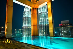 A nighttime view of two illuminated skyscrapers with a pool in the foreground. - Tropicana The Residence KLCC Golden Crown (Kuala Lumpur)