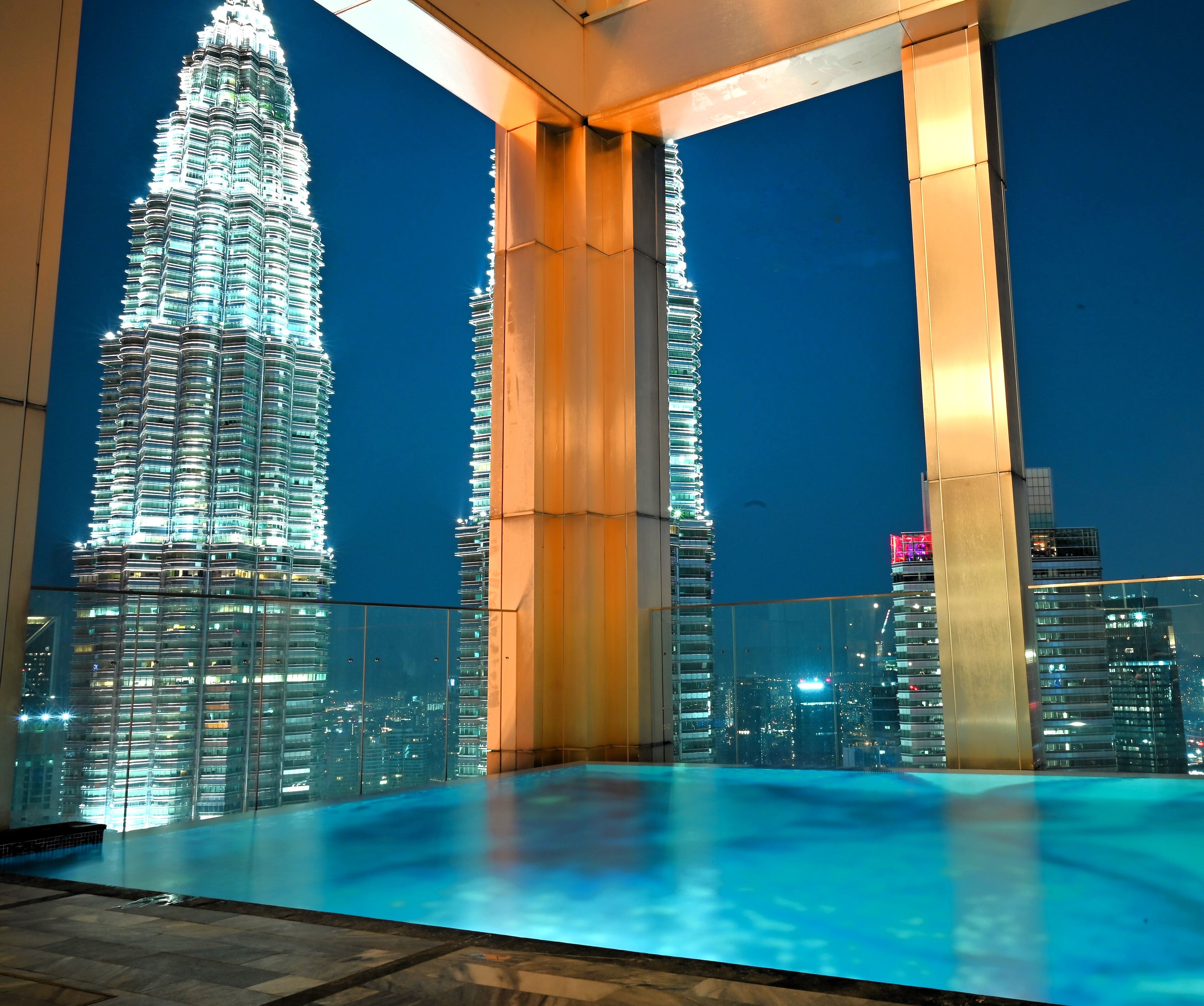 A rooftop pool with a view of the illuminated Burj Khalifa.