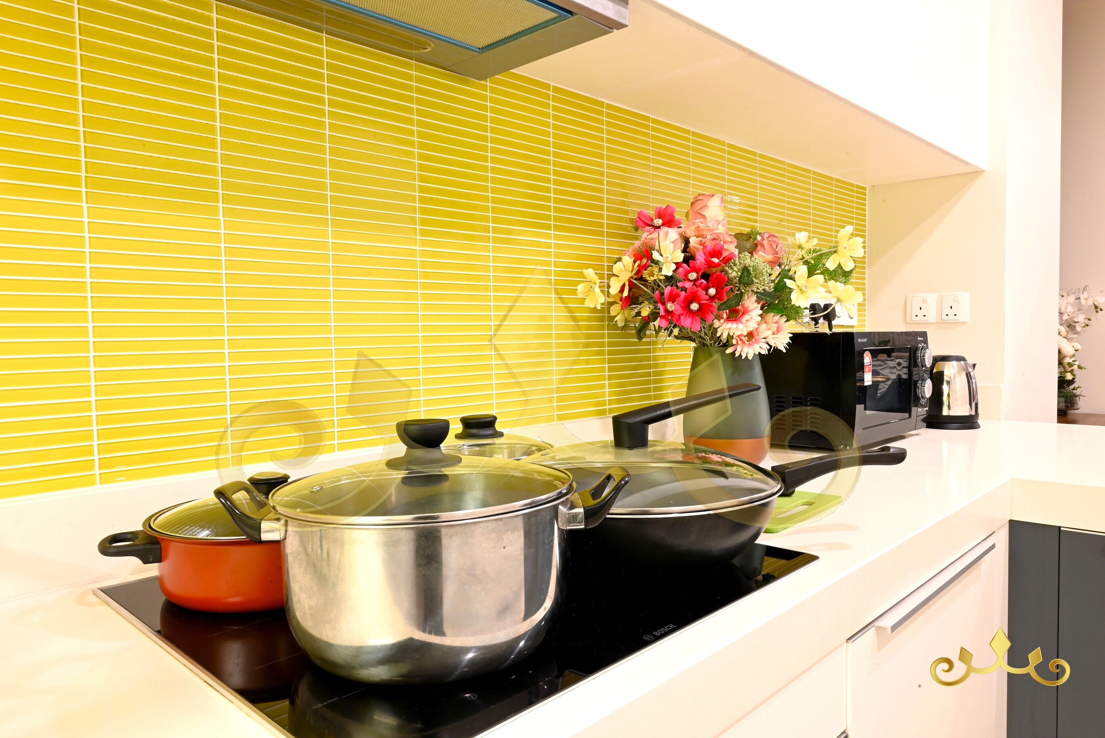 A kitchen with a stove, pots, a coffee maker, and a vase of flowers.