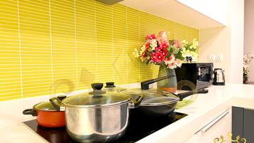 A kitchen with a stove, pots, a coffee maker, and a vase of flowers.