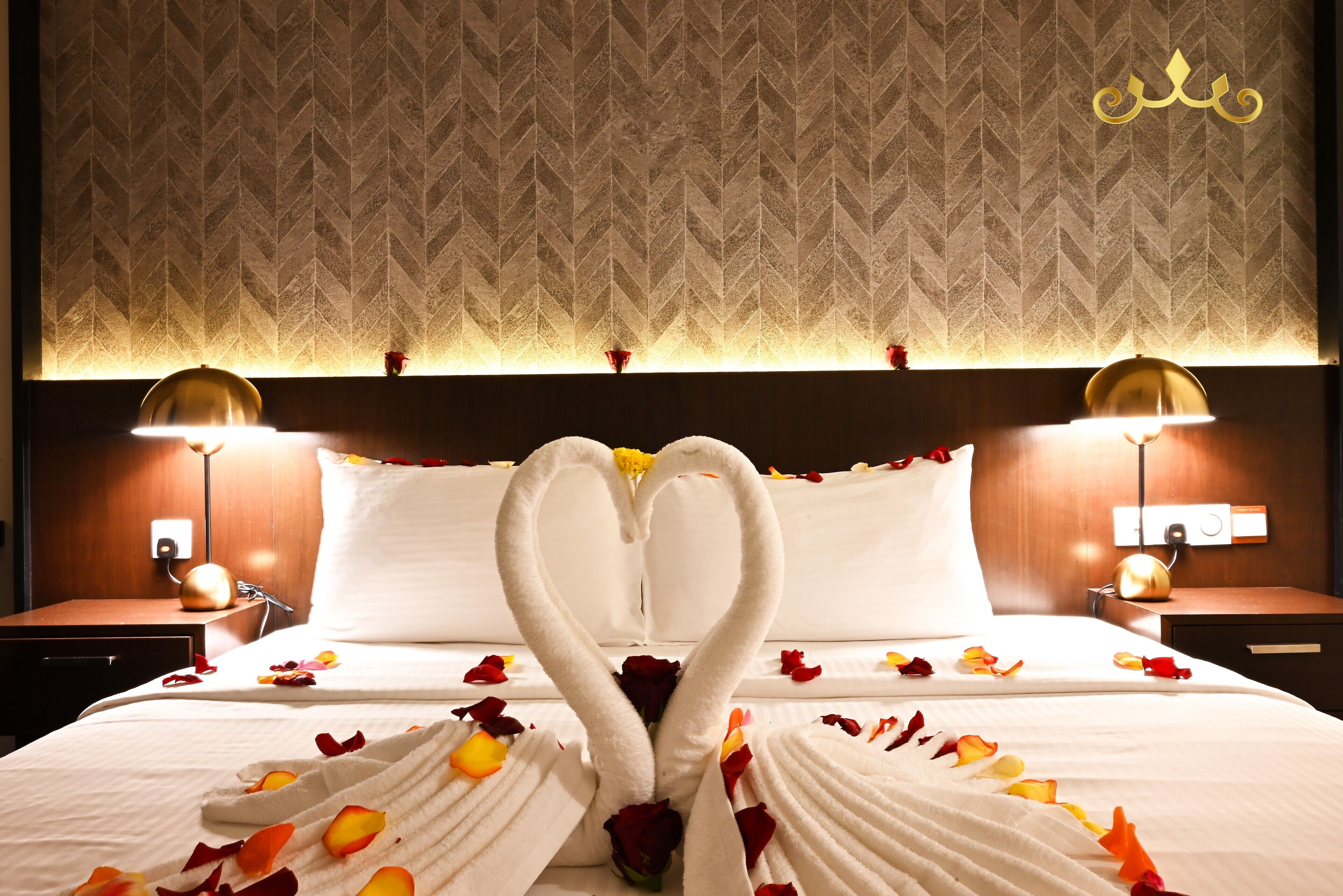 A hotel room with a large bed, two bedside lamps, and a decorative wall pattern.