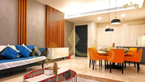 A modern living room with a sofa, dining table, and chairs. There is a kitchen area with a dining table and chairs. - Tropicana The Residence KLCC Golden Crown (Kuala Lumpur)