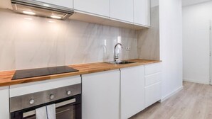 Una cucina moderna con mobili bianchi, un piano di lavoro in legno, un lavello in acciaio inossidabile e un forno.