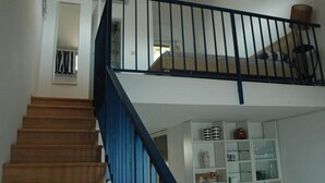 A staircase with a blue handrail leading to a loft bedroom with a bunk bed.
