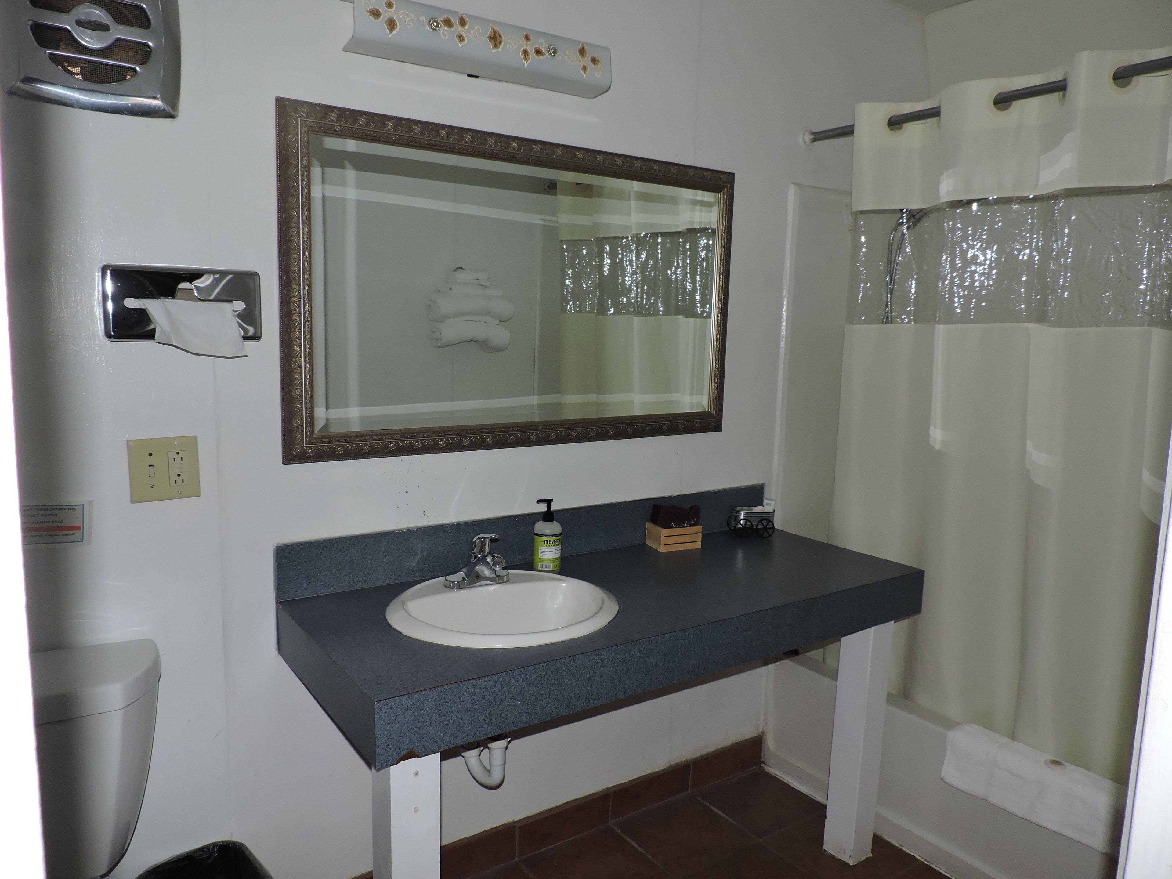 Een badkamer met een wastafel, spiegel en douchegordijn.