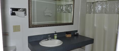 Un baño con lavamanos, espejo y cortina de ducha.