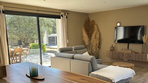 A modern living room with a wooden dining table, a sofa, and a TV mounted on the wall. - Charming villa with pool in Bonifacio (Bonifacio)